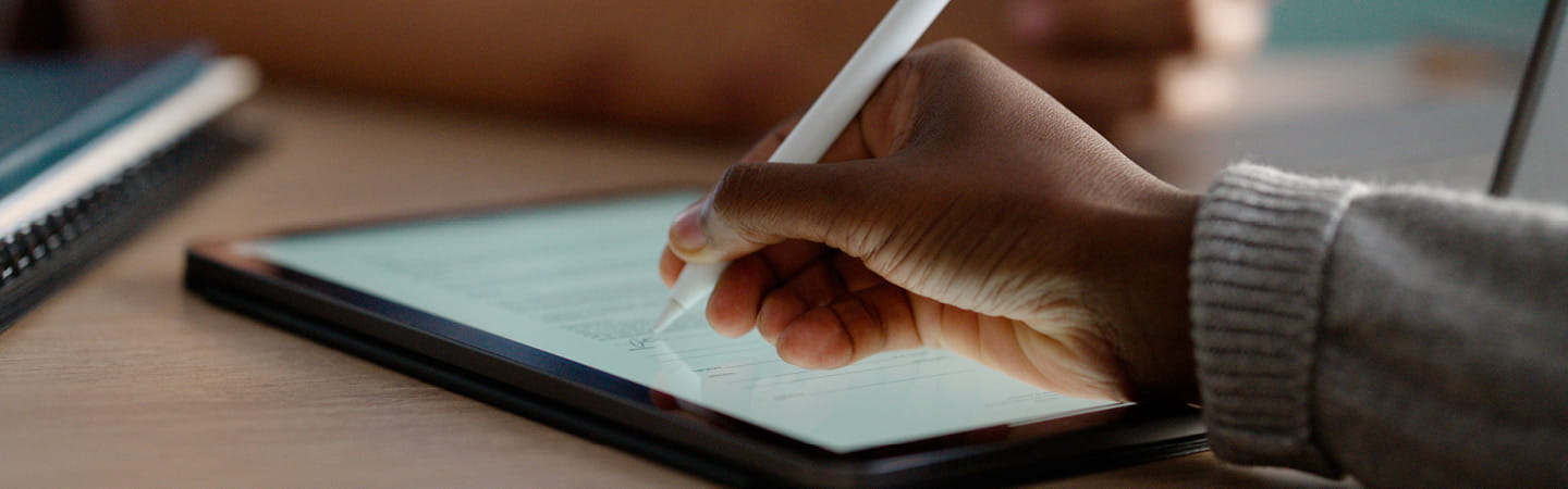 An individual engaged in writing on a tablet with a stylus.