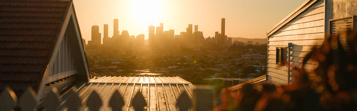 Sunset over Brisbane city skyline from suburban rooftops, used in the Environment and planning year in review 2025