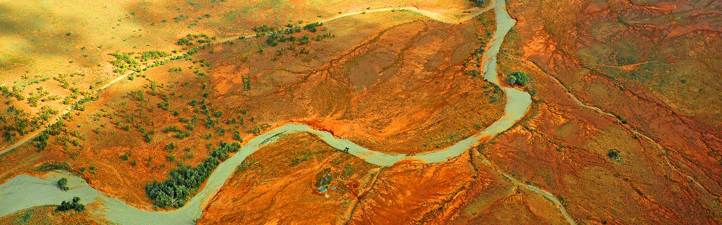 Aerial red outback landscape with turquoise winding river, used in the Environment and Planning Year in Review 2025