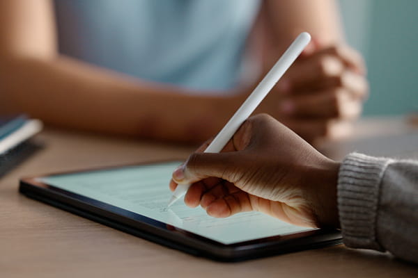 An individual engaged in writing on a tablet with a stylus.
