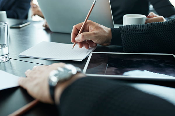 Executive writing notes on table used in Inside the Magellan-Barrenjoey deal M and A article